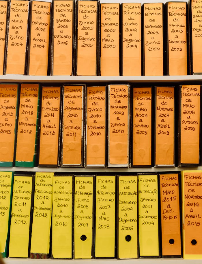 Rows of labeled binder folders on a shelf showcasing organized office files and technical documents.